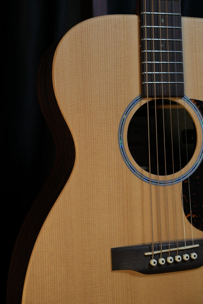 Detail shot of Martin 00-X2E soundhole showing abalone-style rosette and satin-finished spruce top